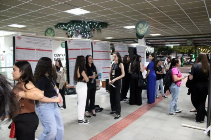 Curso de Contábeis da Unesc reúne alunos em Mostra Científica Estudantes de Ciências Contábeis da Unesc em pé ao lado de banners científicos expostos em um corredor da universidade durante a Mostra Científica.