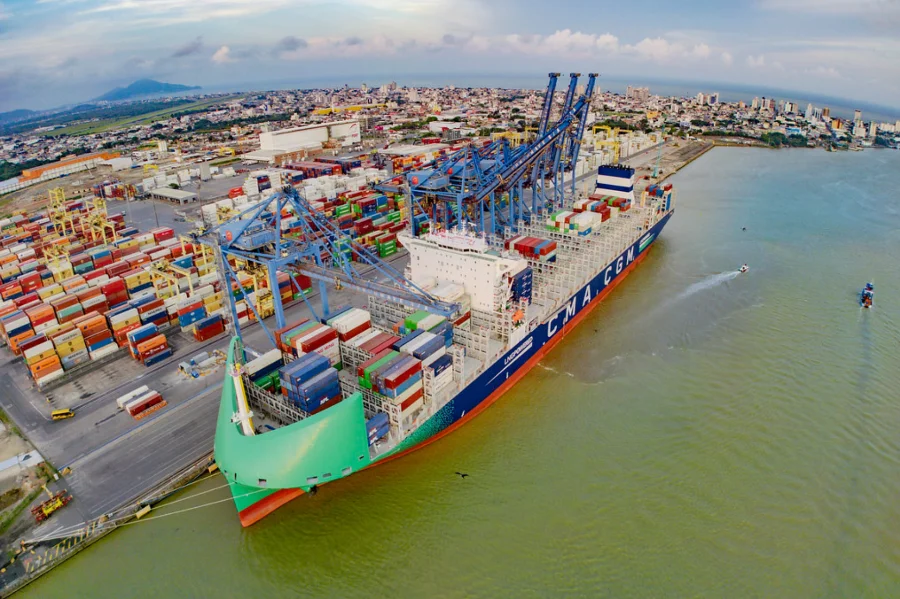 Vista aérea do Porto de Itajaí (ou outro porto catarinense) com um grande navio porta-contêineres sendo carregado/descarregado por guindastes, ilustrando as exportações.