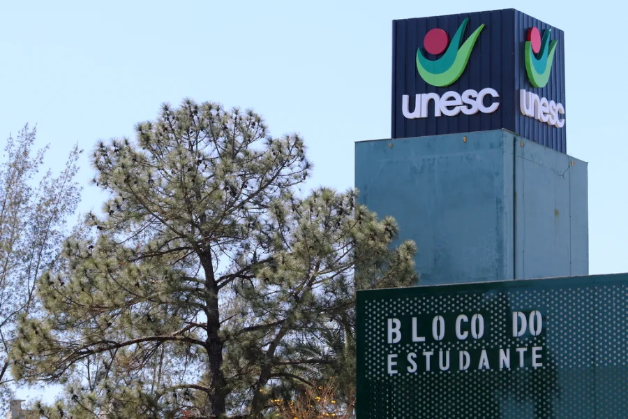 Placa do BLOCO DO ESTUDANTE na Unesc com o logotipo da universidade no topo de um prédio, simbolizando a avaliação institucional.