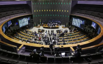 IPVA: Congresso promulga PEC que isenta veículos com 20 anos Vista superior do plenário da Câmara dos Deputados durante sessão, mostrando a disposição semicircular das bancadas e painéis de votação.