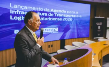 Infraestrutura de SC precisa de R$ 57 bilhões até 2029 O presidente da FIESC, Gilberto Seleme, discursa no púlpito durante o lançamento da Agenda Estratégica para Infraestrutura, com o tema exibido ao fundo.