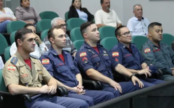 Jiu-Jitsu e Bombeiro Mirim recebem homenagem em Forquilhinha Grupo de bombeiros militares sentados na primeira fila de um auditório durante sessão de homenagem na Câmara de Forquilhinha.