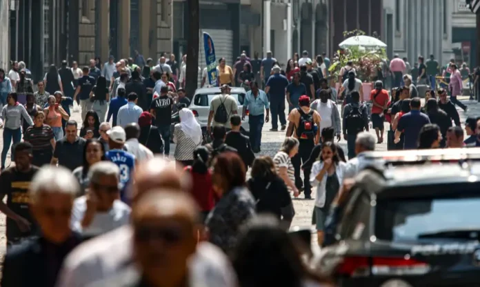 Mais de 8,6 milhões de brasileiros deixaram a linha da pobreza Vista superior de uma rua movimentada com grande concentração de pessoas, ilustrando a população urbana.