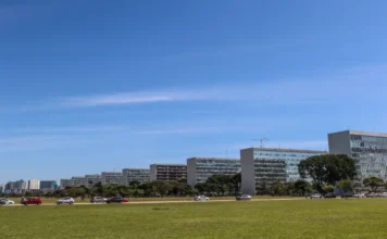 Ministério das Cidades é o único a ter R$ 501 mi liberados Vista panorâmica da Esplanada dos Ministérios, em Brasília, com uma fila de edifícios idênticos do lado direito e área verde em primeiro plano.
