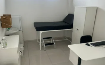 Nova UBS no Arapongas reforça atenção básica em Araranguá Olá! Ótima notícia sobre o avanço na saúde básica de Araranguá com a entrega da nova UBS do Arapongas. Aqui estão as opções de Texto Alt (Texto Alternativo) para a foto do consultório da nova UBS: Opção 1 (Recomendada - Descritiva e Funcional): "Interior de um consultório médico de uma Unidade Básica de Saúde (UBS) recém-inaugurada. O ambiente é claro, com paredes brancas e piso claro. O mobiliário é predominantemente branco e inclui uma maca preta, uma escadinha de dois degraus, uma mesa de trabalho com computador e teclado, e um armário vertical. À esquerda, há uma pia pequena com torneira e dispensador de álcool em gel.