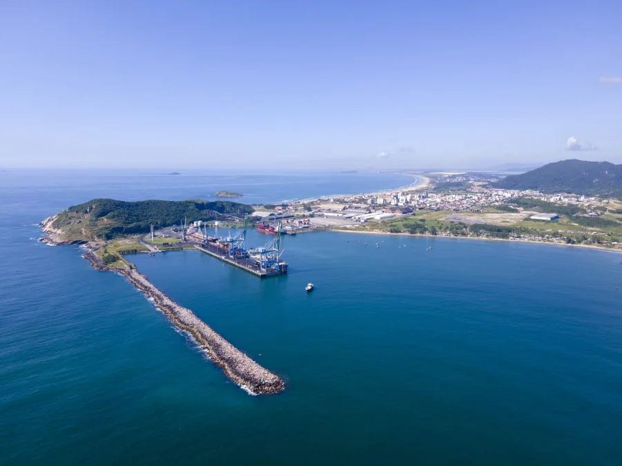 Foto aérea do Porto de Imbituba destacando o molhe de abrigo e guindastes de carga. Governo autoriza R$ 90,5 milhões para obras de recuperação e reforço estrutural, parte de um pacote de investimentos de R$ 300 milhões.