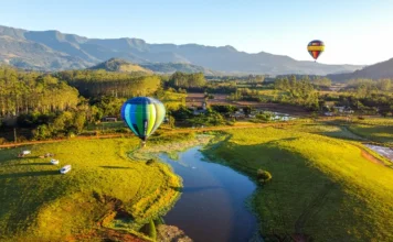Praia Grande é 1ª no país a concluir regulamentação de balões Vista aérea panorâmica de Praia Grande com dois balões de ar quente flutuando sobre um vale verde e um rio, com montanhas e cânions ao fundo.
