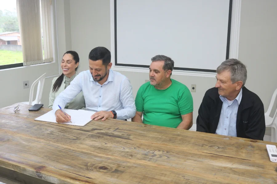 O vereador Jailson Mota Luiz, presidente da Câmara, assina o termo de posse como prefeito interino de Santa Rosa do Sul, ao lado de autoridades.