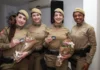 Rede Catarina: Curso foca em estudos de gênero e saúde mental Quatro policiais militares femininas formandas da Rede Catarina, uniformizadas, seguram buquês de flores e sorriem na formatura em Florianópolis.
