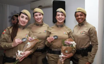 Rede Catarina: Curso foca em estudos de gênero e saúde mental Quatro policiais militares femininas formandas da Rede Catarina, uniformizadas, seguram buquês de flores e sorriem na formatura em Florianópolis.