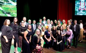 Reitora da Unesc recebe Cidadania Benemérita de Criciúma Gisele Silveira Coelho Lopes (reitora) e grupo de líderes e colegas posam juntos no palco do Teatro Elias Angeloni, celebrando a Cidadania Benemérita.