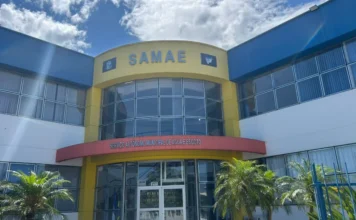 SAMAE de Araranguá abre seletivo com salários de até R$ 8,8 mil Fachada da sede do SAMAE (Serviço Autônomo Municipal de Água e Esgoto) de Araranguá, em prédio amarelo e azul, sob luz do sol.