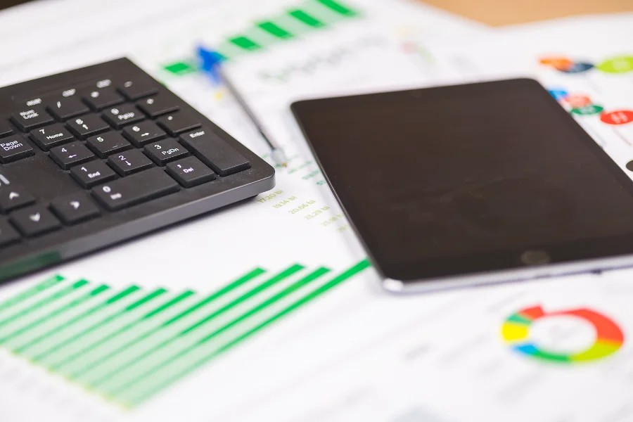 Gráficos financeiros e teclado de computador. Santa Catarina atinge investimento recorde de R$ 5,5 bilhões em 2025 e mantém nota máxima CAPAG A+ do Tesouro Nacional.