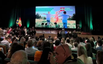 Santa Rosa do Sul garante R$ 676 mil para projeto de idosos Plenária lotada em evento com autoridades no palco, onde uma tela de LED exibe a mensagem "Projetos contemplados no Fundo da Infância e da Adolescência (FIA)".