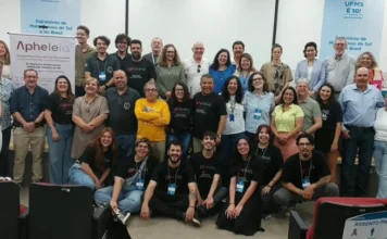 Unesc participa de seminário internacional com 7 países na UFMS Grande grupo de pesquisadores e professores posando para foto em um auditório, com banners do evento Apheleia e da UFMS ao fundo.