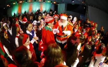 Unesc reúne 200 músicos em tradicional Cantata de Luz O Papai Noel, de microfone, abraça crianças e jovens coralistas no palco da Cantata de Luz da Unesc.