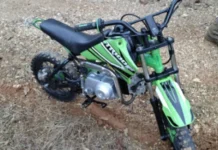 Urussanga: Adolescente cai de mini-moto ao fugir da PM Fotografia de uma mini-moto de 50 cilindradas, modelo TRX, nas cores verde e preta, caída sobre uma estrada de terra e brita. O veículo apresenta pneus de cravos sujos de lama e guidão preto. Ilustra a apreensão em Urussanga.