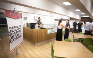 ALESC e Senac iniciam operação de restaurante-escola Fotografia do ambiente interno da nova lanchonete no Palácio Barriga Verde, exibindo balcões de atendimento, funcionários do Senac uniformizados e clientes em um espaço moderno e iluminado.