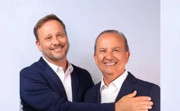 Adriano Silva aceita ser pré-candidato a vice de Jorginho Adriano Silva, prefeito de Joinville, e Jorginho Mello, governador de Santa Catarina, posam juntos e sorridentes para foto, oficializando a pré-candidatura de Silva a vice-governador na chapa de Mello para as eleições de 2026. Ambos vestem paletó azul-marinho e camisa branca. Adriano Silva, à esquerda, abraça Jorginho Mello, à direita, em um gesto de união política. O fundo é liso em tom azul-claro.
