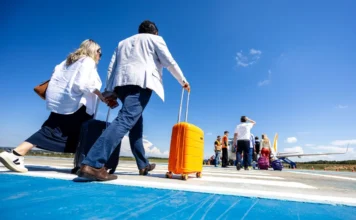 Aeroportos de SC batem recorde histórico de passageiros "Passageiros com malas caminham pela pista de um aeroporto em Santa Catarina em direção a uma aeronave, ilustrando a movimentação recorde de 8,5 milhões de viajantes no estado em 2025."