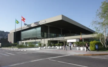 Alesc celebra um ano da posse de novos servidores Fachada ensolarada do Palácio Barriga Verde, sede da Assembleia Legislativa de Santa Catarina (Alesc) em Florianópolis. O prédio moderno de vidro e concreto possui bandeiras hasteadas e o nome da instituição na frente, sendo o local de trabalho dos servidores que completam um ano de posse.