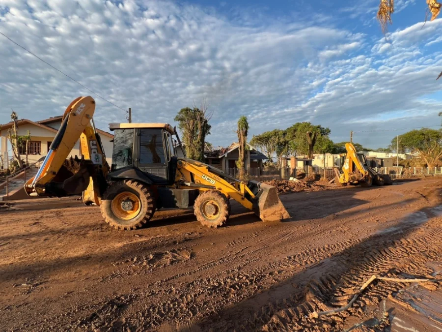 Alesc foca em clima e proteção animal em 2025 Retroescavadeiras trabalham na limpeza e remoção de lama e destroços em via pública após uma enchente, ilustrando a importância da nova legislação catarinense que facilita o intercâmbio de máquinas e auxílio entre municípios em situações de desastres naturais.