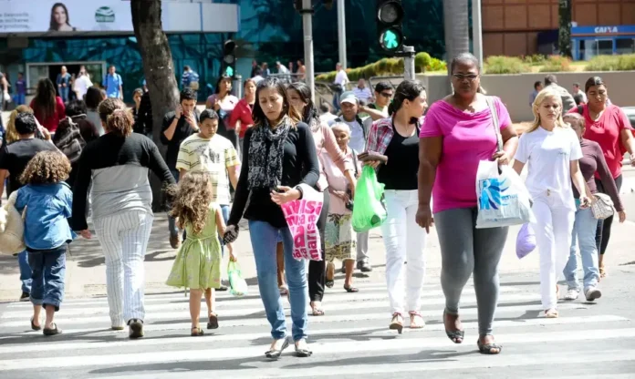 Brasil atinge desemprego recorde de 5,1% no fim de 2025 Movimentação de pessoas atravessando uma faixa de pedestres em um centro urbano, ilustrando a dinâmica da população ocupada no Brasil em meio à queda da taxa de desemprego.