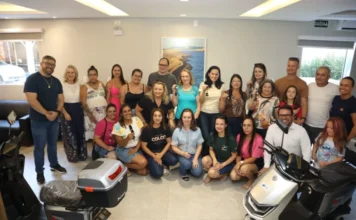 CDL Araranguá entrega 20 scooters do Natal Premiado Foto oficial da entrega de prêmios da CDL Araranguá. Um grupo de pessoas, entre ganhadores e representantes da entidade, posa sorridente em uma sala ampla. Em destaque, no primeiro plano, aparecem duas scooters elétricas prateadas da campanha Natal Premiado.