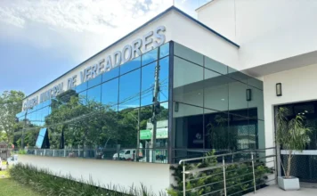 Câmara de Araranguá adota horário especial em janeiro Fachada externa do prédio moderno da Câmara Municipal de Vereadores de Araranguá, com vidros espelhados refletindo o céu e árvores.