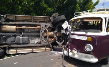 Colisão entre S-10 e Kombi deixa três feridos em Criciúma Fotografia do local do acidente na Rua Arcângelo Meller, em Criciúma. Em primeiro plano, uma caminhonete Chevrolet S-10 branca aparece tombada lateralmente na pista. Próximo a ela, um Volkswagen Kombi apresenta danos na parte frontal. Ao fundo, viaturas vermelhas do Corpo de Bombeiros (CBMSC) e profissionais de resgate com coletes reflexivos realizam o atendimento às vítimas em uma rua de bairro residencial.