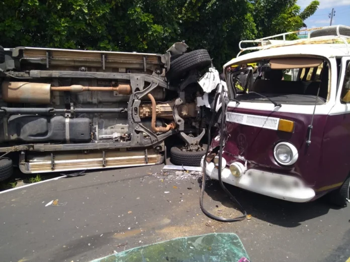 Colisão entre S-10 e Kombi deixa três feridos em Criciúma Fotografia do local do acidente na Rua Arcângelo Meller, em Criciúma. Em primeiro plano, uma caminhonete Chevrolet S-10 branca aparece tombada lateralmente na pista. Próximo a ela, um Volkswagen Kombi apresenta danos na parte frontal. Ao fundo, viaturas vermelhas do Corpo de Bombeiros (CBMSC) e profissionais de resgate com coletes reflexivos realizam o atendimento às vítimas em uma rua de bairro residencial.