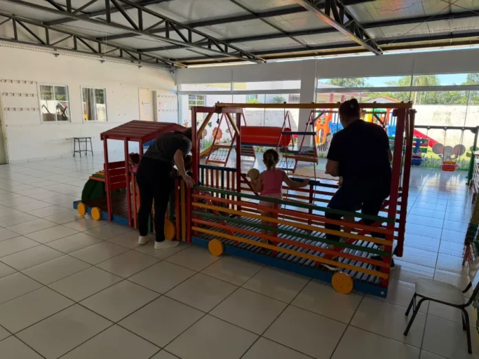 Colônia de Férias em Turvo apoia pais que trabalham no verão Monitoras acompanham crianças em brinquedo de madeira na Colônia de Férias de Turvo. Projeto atende 120 crianças em janeiro de 2026 no CEI Vânia Maria Zaccaron Manfredini para apoiar pais que trabalham no verão.