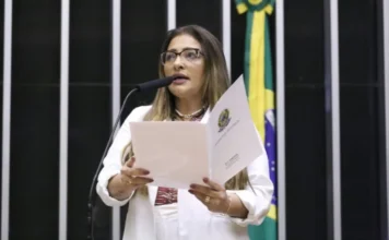 Comissão aprova prazo maior para gestantes tirarem CNH A deputada federal Ely Santos, relatora do projeto, discursa na Câmara dos Deputados segurando o parecer oficial. Ela é uma mulher de cabelos castanhos, usa óculos de grau e blazer branco. Ao fundo, vê-se parte da bandeira do Brasil. A imagem ilustra a aprovação da proposta que beneficia candidatas gestantes no processo da CNH.