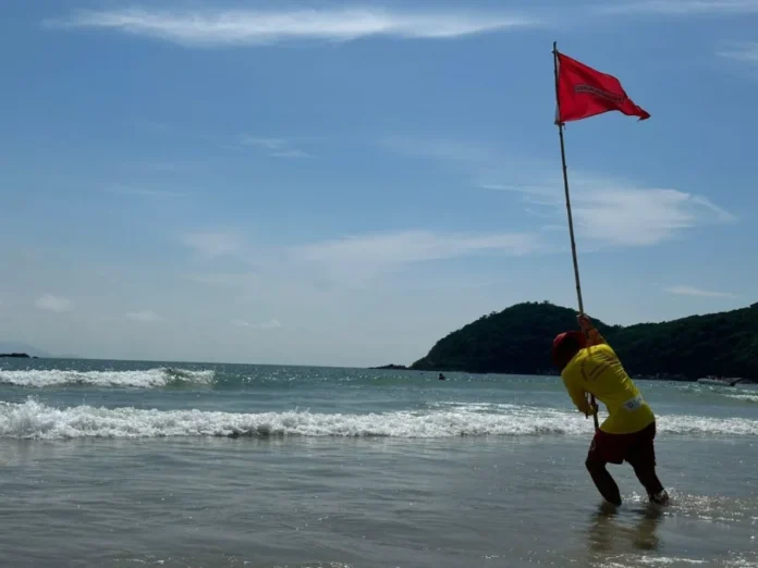 Correntes de retorno saiba identificar o perigo no mar Guarda-vidas em praia de Santa Catarina demarcando uma área de risco com bandeira vermelha, uma ação preventiva essencial mencionada na matéria para alertar banhistas sobre o perigo das correntes de retorno.