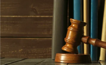 Crimes em série: homem pega 106 anos de prisão no Sul Martelo de juiz sobre base de madeira com livros jurídicos ao fundo, simbolizando a sentença judicial de 106 anos de prisão para o estuprador em série na comarca de Araranguá.