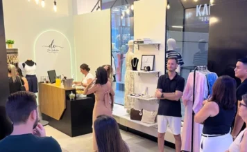 Dai Valentim inaugura loja no Sombrio Moda Shopping Interior de uma loja de roupas femininas durante um evento, com mulheres circulando, uma mesa redonda branca com doces e salgados, e um balcão de atendimento com bebidas.