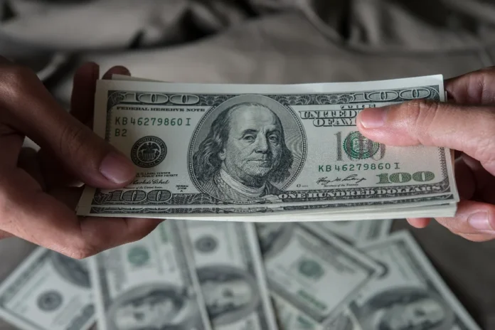 Dólar fecha a R$ 5,37 e registra quarta queda seguida Close de duas pessoas segurando um maço de notas de 100 dólares americanos. A imagem ilustra a cotação da moeda, que fechou em queda de 0,48%, vendida a R$ 5,37.