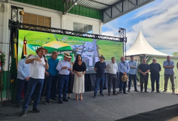 Governador Jorginho Mello gesticula enquanto fala aos produtores rurais em Turvo, acompanhado no palco por autoridades pol&iacute;ticas e organizadores do evento da Dagostin Sementes.