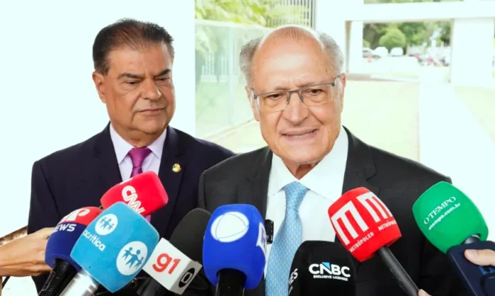Governo mantém envio de acordo à Câmara após trava da UE O vice-presidente da República, Geraldo Alckmin, em primeiro plano, fala a um grupo de jornalistas, com vários microfones de emissoras de rádio e televisão à sua frente. Ele veste terno escuro e gravata azul clara. Atrás dele, à esquerda, observa o senador Nelsinho Trad, também de terno e gravata. A cena ocorre em um ambiente externo, com um prédio ao fundo, após uma reunião sobre o acordo comercial entre Mercosul e União Europeia.