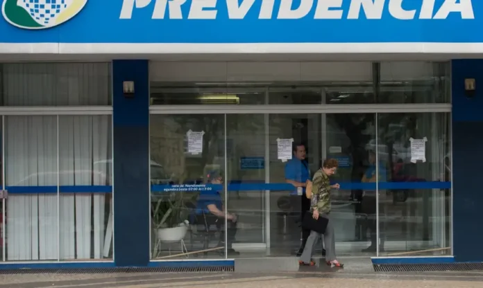 INSS fecha agências para manutenção de sistemas da Dataprev Entrada de uma agência do INSS com aviso na porta sobre a suspensão temporária do atendimento presencial para manutenção de sistemas.
