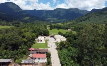 Jacinto Machado conclui obras em duas comunidades rurais Vista aérea de uma comunidade rural situada entre montanhas no interior de Jacinto Machado, representando as localidades de Pinheirinho Alto e Costão da Pedra, que foram beneficiadas com as obras de infraestrutura descritas na matéria.