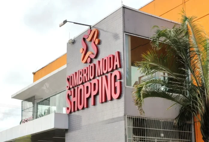 Liquida Verão Sombrio Moda Shopping tem descontos de 50% Fachada externa do Sombrio Moda Shopping, com letreiro em vermelho e logomarca, em um prédio de arquitetura moderna e palmeira na lateral direita.