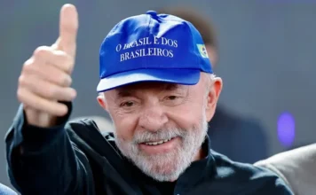 Lula celebra acordo UE-Mercosul: ‘Vitória do diálogo’ Presidente Luiz Inácio Lula da Silva sorrindo e fazendo um sinal de positivo com o polegar da mão direita. Ele veste uma camisa escura e usa um boné azul com a bandeira do Brasil na lateral e a frase 'O Brasil é dos Brasileiros' bordada em branco na frente.