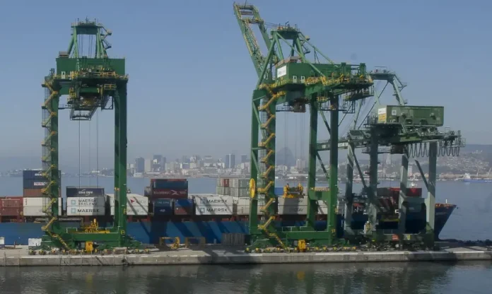 Mercosul-UE entidades celebram acordo histórico Grandes guindastes verdes em um porto movimentado com contêineres e um navio, com a cidade ao fundo.