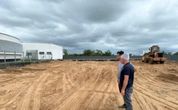 Obras do estacionamento da Câmara avançam em Araranguá "Presidente da Câmara de Vereadores de Araranguá, Paulinho Souza, vistoria o canteiro de obras do novo estacionamento da Casa Legislativa, atualmente em fase de terraplanagem. Ao fundo, observa-se o prédio da Câmara e um trator."