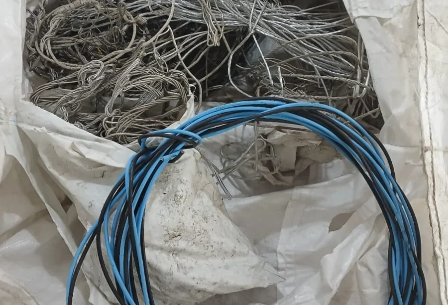 Saco de ráfia branco contendo diversos rolos de cabos de cobre e fios elétricos e telefônicos apreendidos em operação policial.