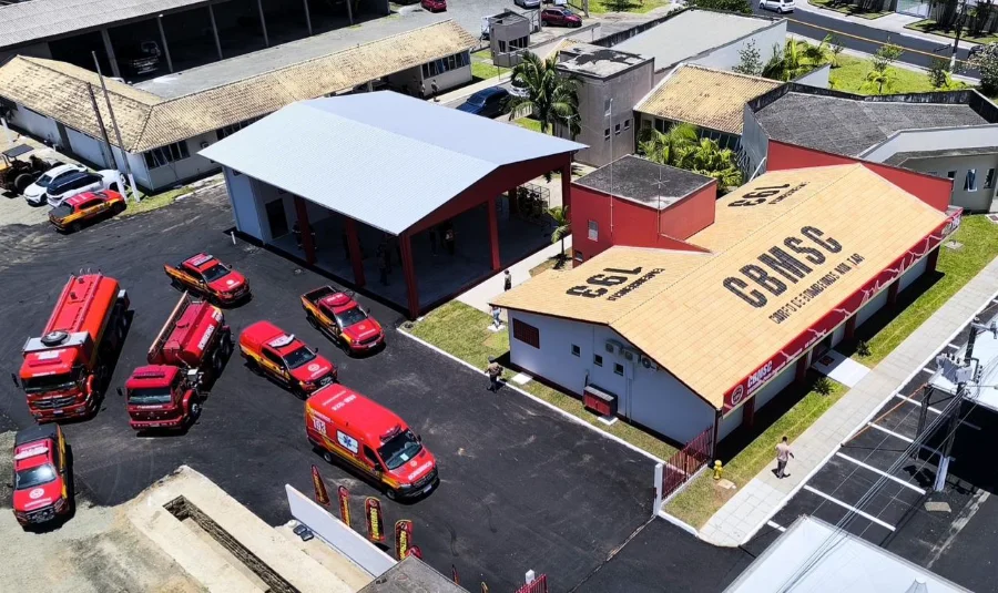Vista aérea do Posto Avançado do Corpo de Bombeiros no Rio Maina, em Criciúma, exibindo a estrutura do quartel e o pátio com diversas viaturas, caminhões de combate a incêndio e ambulâncias estacionadas.