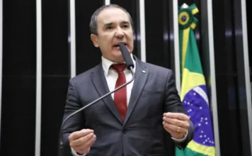 Projeto de lei prevê folga remunerada no aniversário O deputado federal Duda Ramos (MDB-RR), autor do Projeto de Lei 886/25 que propõe folga remunerada no aniversário do trabalhador, discursa ao microfone no plenário da Câmara dos Deputados, com a bandeira do Brasil ao fundo.