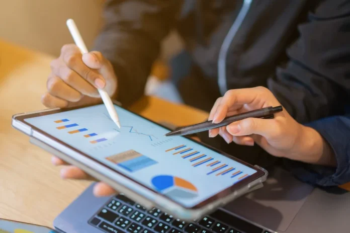 Renda de empreendedores em SC supera média nacional em 38% Close de mãos analisando gráficos e estatísticas de negócios na tela de um tablet, ilustrando o levantamento do Sebrae/SC sobre o perfil e a renda dos empreendedores catarinenses.
