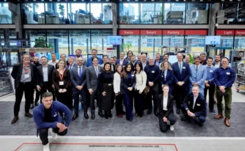 SC amplia parcerias econômicas em missão na Europa Membros da comitiva oficial de Santa Catarina, liderada pela vice-governadora Marilisa Boehm, posam para foto em grupo ao lado de empresários e autoridades suíças no interior da Swiss Smart Factory. O ambiente é amplo e tecnológico, com paredes de vidro e equipamentos industriais ao fundo, simbolizando a cooperação em inovação e tecnologia entre o Estado e o Cantão de Berna.